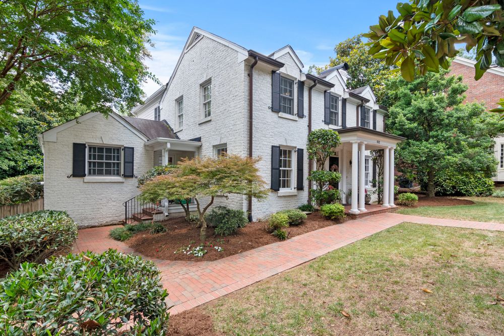 A brick home with a landscaped front yard, walkway and welcoming entrance